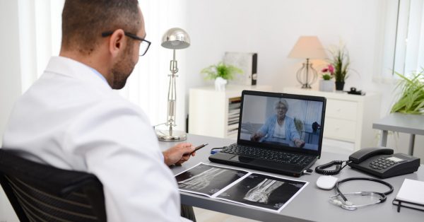 handsome doctor giving a remote medical consultation with senior woman patient over internet computer telemedecine diagnostic